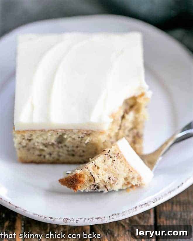 Sour Cream Banana Cake - a tender banana cake topped with a luscious layer of cream cheese frosting! Bite of sour cream banana cake on a fork on a white plate.