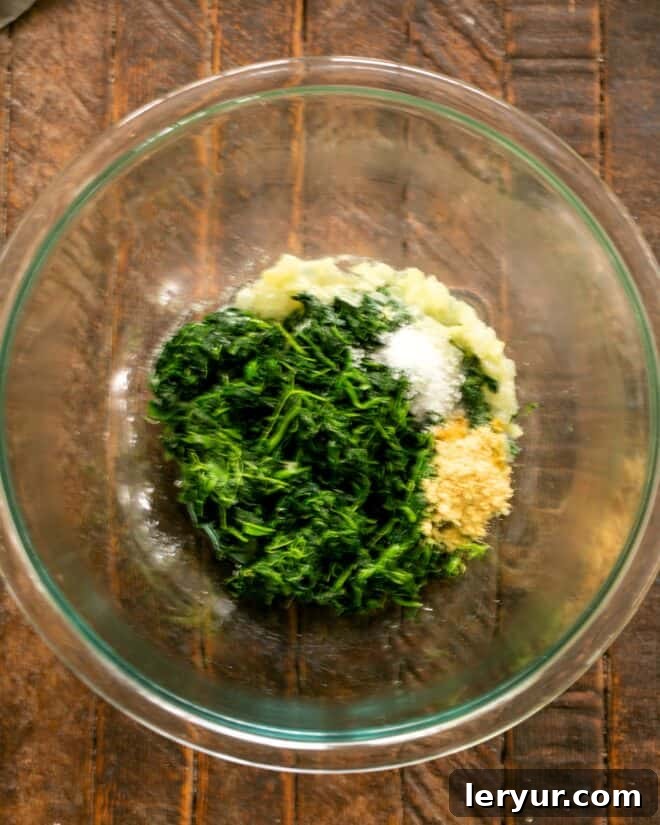 Defrosted spinach, softened onions, dry mustard, and salt in a mixing bowl.