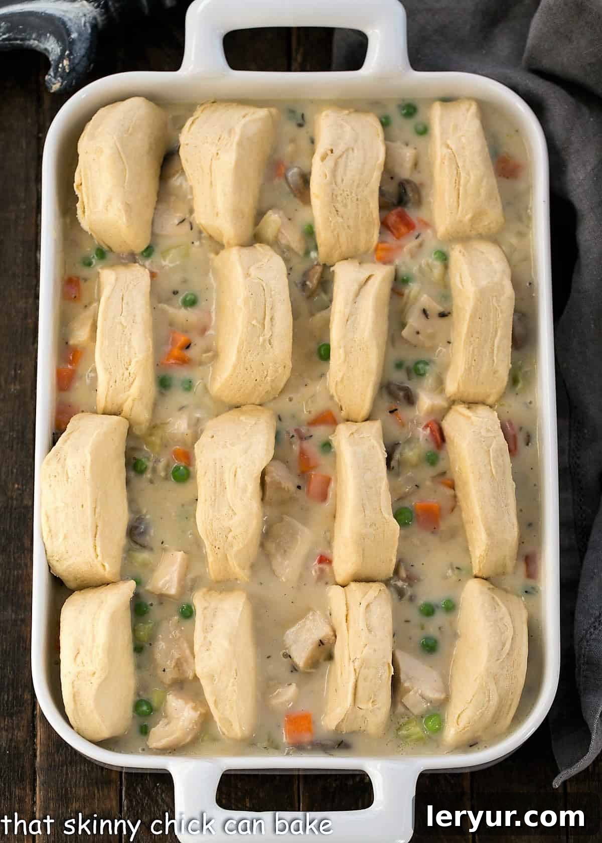 Hearty Homestyle Chicken Pot Pie 4 A close-up view showing how to artfully arrange cut biscuit halves on top of the hot chicken pot pie filling in a casserole dish.