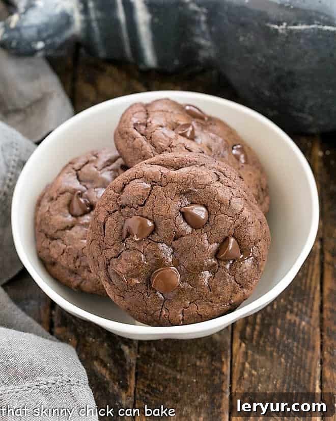 Chocolate Chunk Cookies - the perfect treat for a chocoholic Three decadent double chocolate cookies in a white bowl, showcasing their rich color and melted chocolate chunks.
