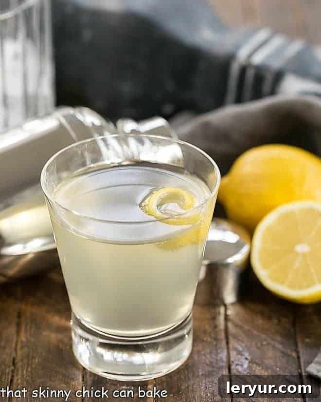 French 75 Champagne Cocktail - a festive citrus sparkler with gin, lemon juice, simple syrup and champagne! Sure to dazzle anyone who takes a sip! French 75 Champagne Cocktail with a lemon twist in a highball glass, showcasing the drink's refreshing clarity.
