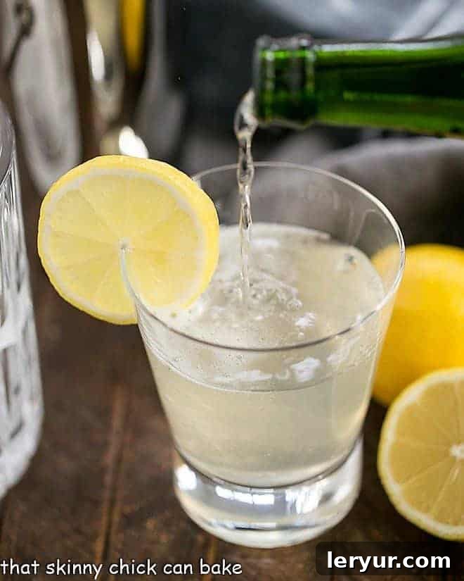 French 75 Champagne Cocktail - a festive citrus sparkler with gin, lemon juice, simple syrup and champagne! Sure to dazzle anyone who takes a sip! French 75 Champagne Cocktail garnished with a slice of lemon, sparkling brightly in a elegant glass.