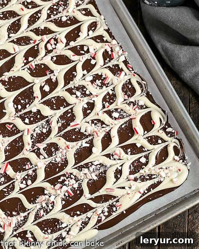 Swirled Peppermint Bark cooling on a parchment-lined sheetpan, ready to be broken into pieces.