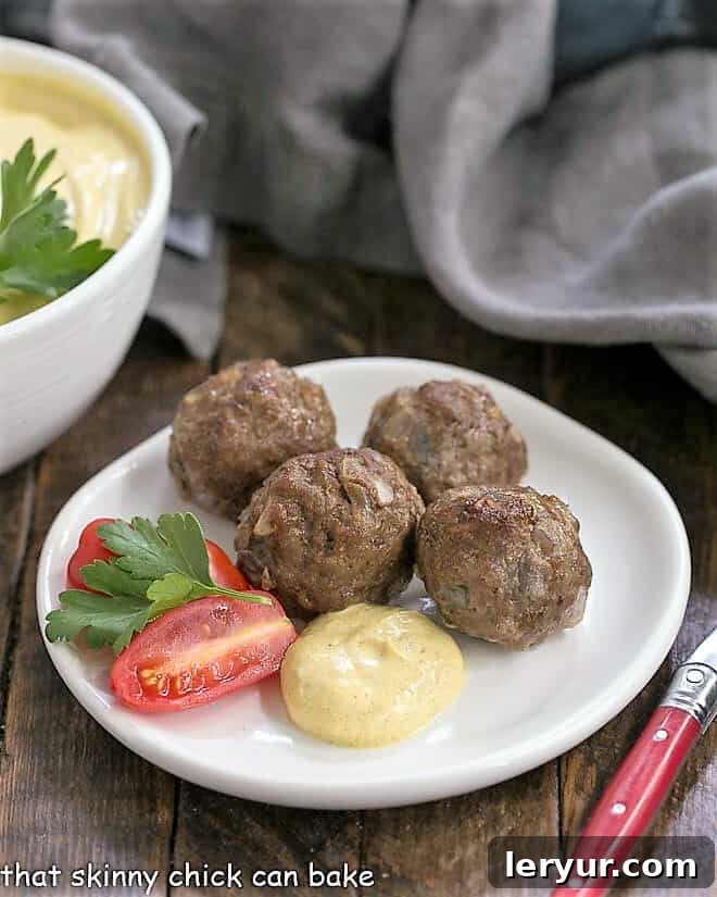 Indian Meatballs with Yogurt Sauce are a twist on cocktail meatballs with an Asian flair! Indian Meatballs with Yogurt Sauce presented on a white appetizer plate, ready to serve.