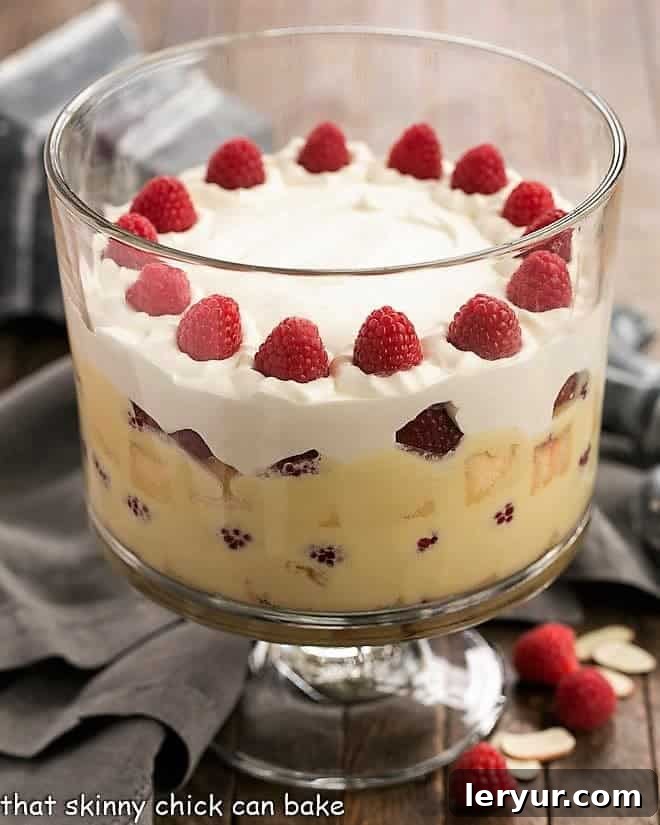 Traditional English Trifle topped with a generous layer of whipped cream and fresh raspberries.
