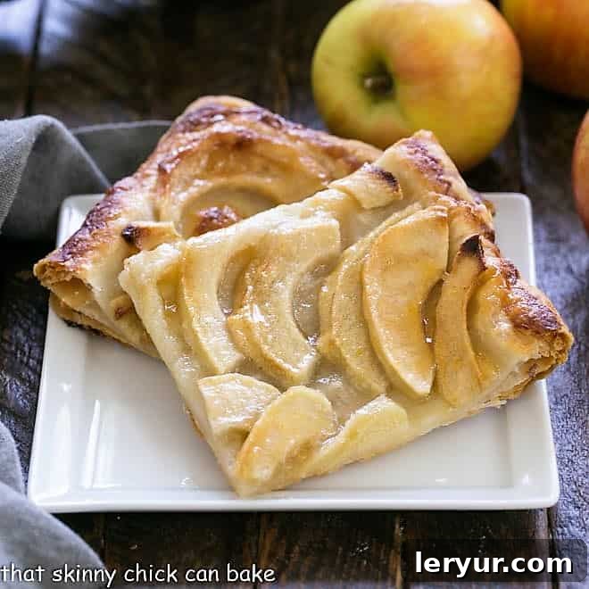 2 slices of a beautiful French apple tart on a square white ceramic plate, ready to be enjoyed.