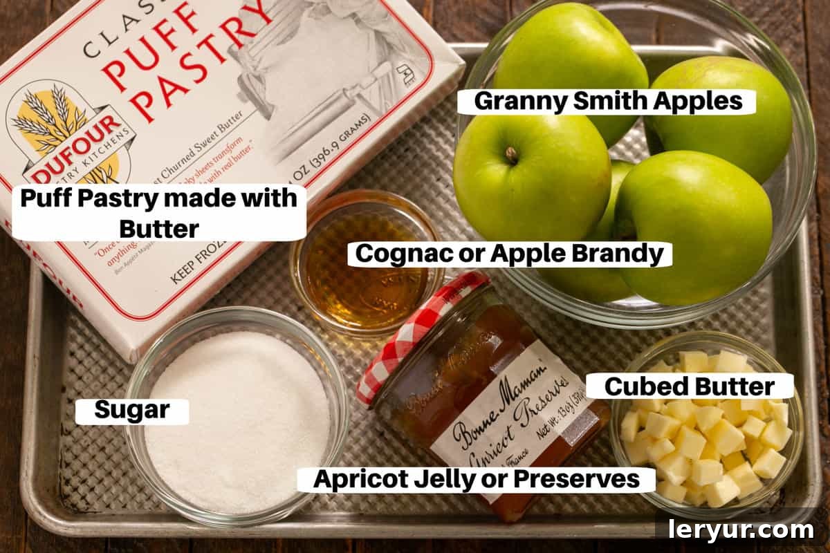 Fresh ingredients for a French Apple Tart, including puff pastry, sliced Granny Smith apples, sugar, butter, and apricot jelly, neatly arranged on a baking sheet.
