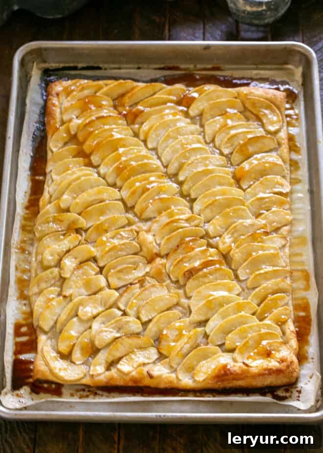 A warm French Apple Tart being brushed with a glossy apricot glaze.