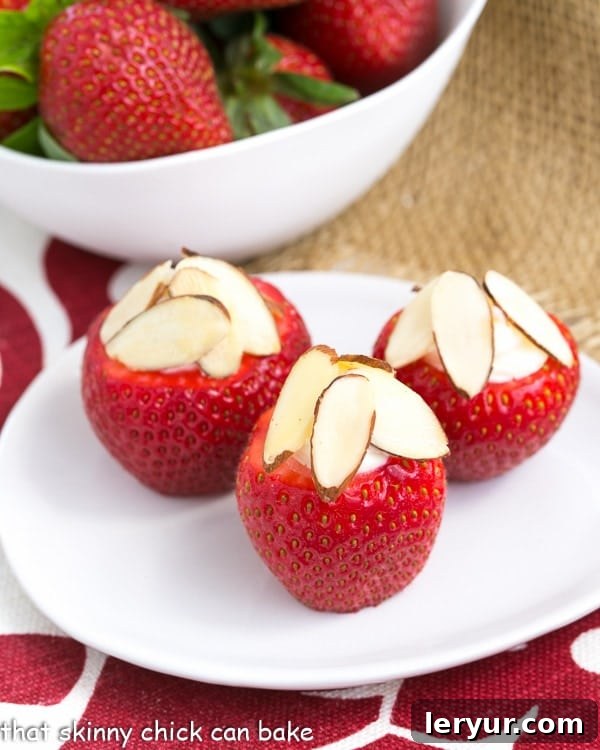 Cheesecake Stuffed Strawberries on a small oval plate topped with sliced almonds, ready for a delightful indulgence.