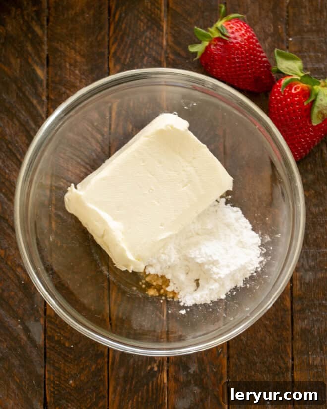 Filling ingredients for stuffed strawberries in a bowl, including cream cheese, powdered sugar, and vanilla extract.
