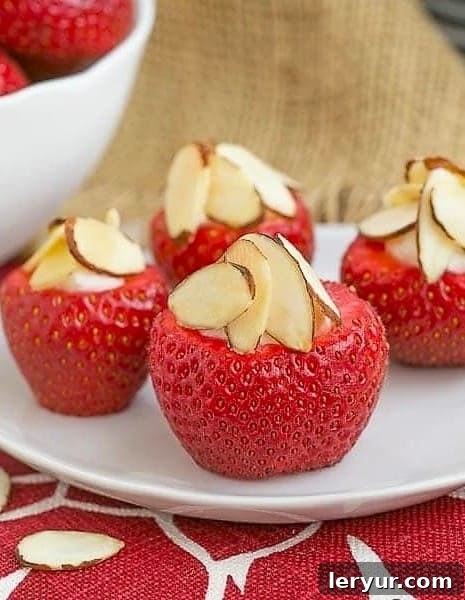 Stuffed strawberries on a small white plate, garnished with slivered almonds and ready to be served.