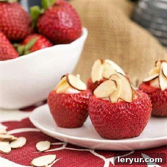 Cheesecake stuffed strawberries on a small white plate, garnished with almonds.