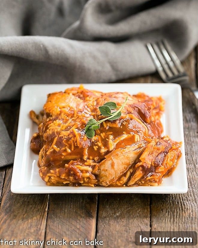 Easy Turkey Enchilada Casserole - super simple casserole with tortillas, turkey, enchilada sauce and cheese for a warm, comforting meal! Close-up of a slice of Easy Turkey Enchilada Casserole on a white plate, showing the cheesy top and layered interior
