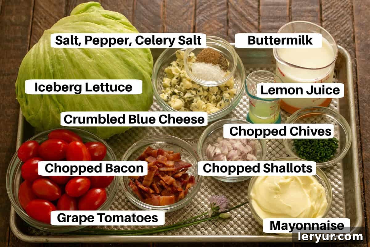 Wedge Salad Ingredients with labels on a metal sheet pan, showing fresh iceberg lettuce, blue cheese, bacon, tomatoes, and dressing components.