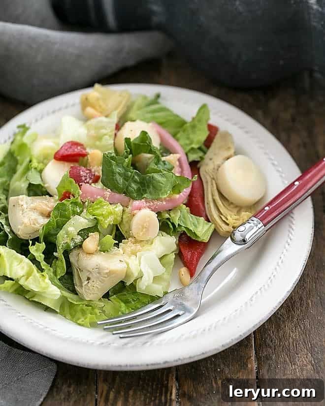 A vibrant Italian Chopped Salad served on a white salad plate with a red-handled fork, showcasing its fresh ingredients and rich colors.
