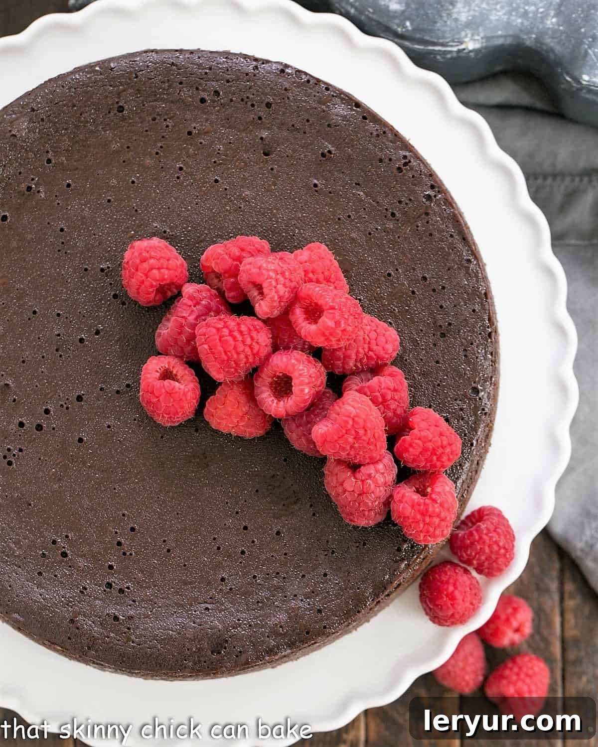 Flourless Chocolate Kahlua Cake - An exquisite, dense cake infused with coffee liqueur Overhead view of a beautifully presented Flourless Chocolate Kahlua Cake, adorned with fresh raspberries, centered on an elegant cake stand.