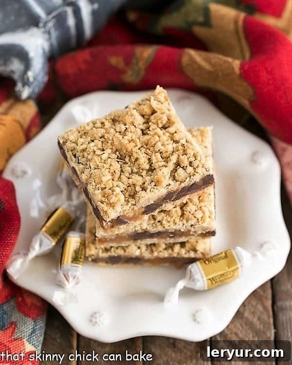 Oatmeal Carmelitas have an oat crust and oat streusel sandwiching a gooey layer of both caramel and chocolate. This easy oat bars recipe with caramel makes the perfect dessert for any occasion! #caramel #dessert #oatmeal Overhead image of Oatmeal Caramel Bars stacked onto a dessert plate.