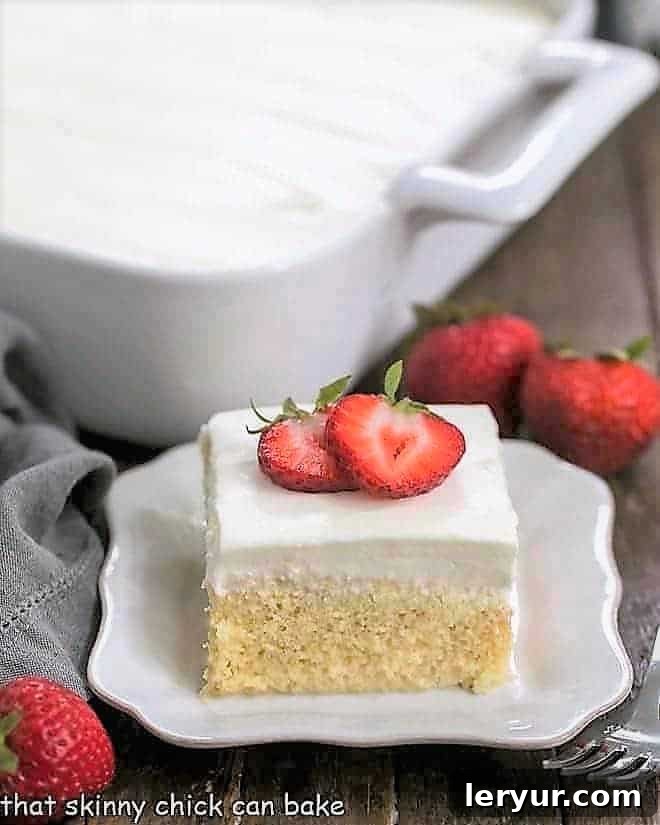 Authentic Tres Leches Cake - A Latin American favorite make with 3 milks, a homemade sponge cake and whipped cream frosting! Authentic Tres Leches Cake slice on a square plate with full cake in the background.