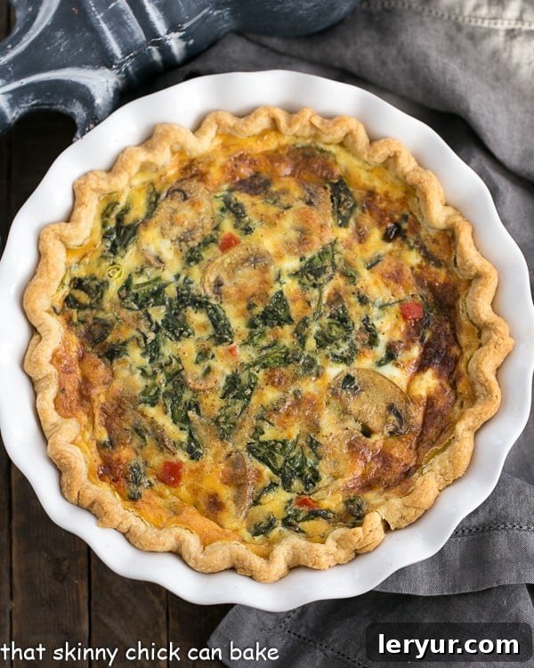 Spinach Mushroom Quiche - A rich, tender quiche full of cheese and vegetables A golden-brown Spinach Mushroom Quiche resting in a white ceramic pie plate, fresh out of the oven, with its savory filling perfectly set and a slightly puffed, inviting crust.