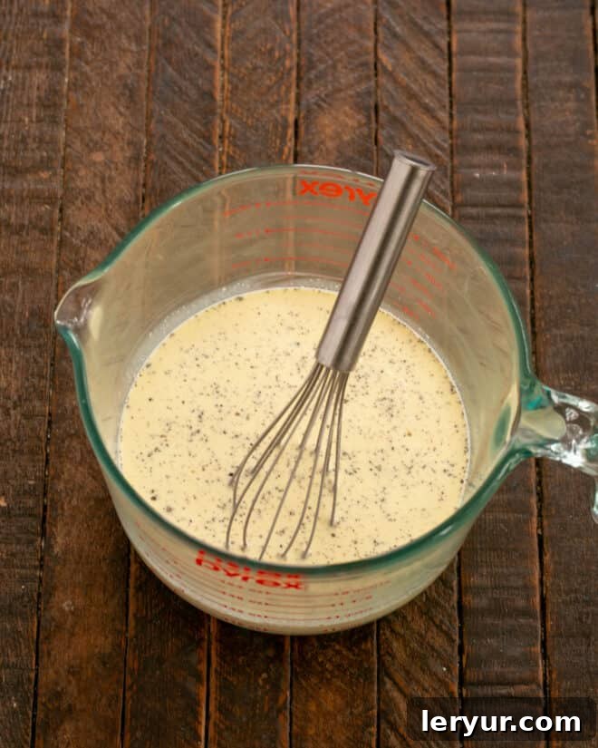 Garden & Woodland Quiche 5 Ingredients for quiche custard, including eggs, half and half, heavy cream, salt, and pepper, being whisked together in a bowl.