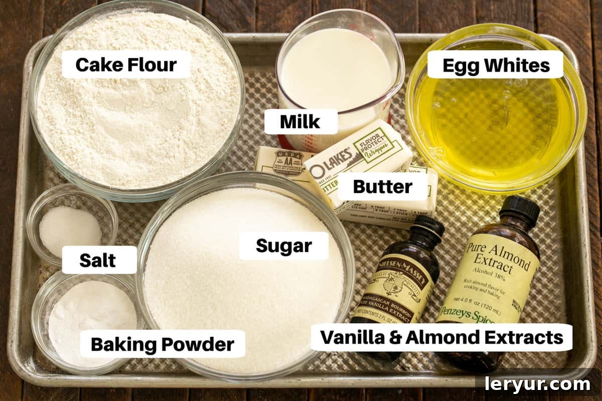 A beautiful arrangement of all the dry and wet ingredients required for the white layer cake, meticulously organized on a sheet pan with clear labels for easy identification.