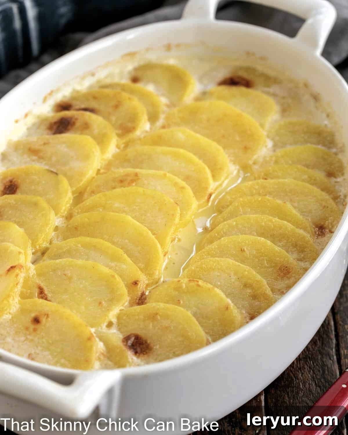 The Best Scalloped Potatoes - Tender, cheesy and perfect every time! Oval casserole dish of golden brown scalloped potatoes, ready to serve.