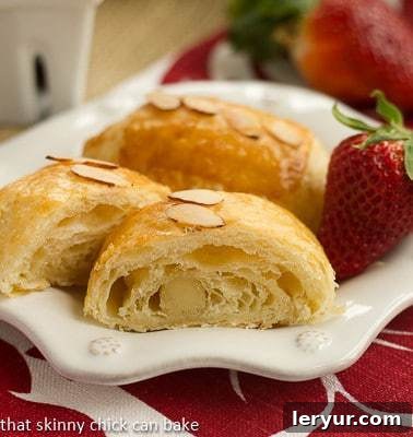 Almond croissants on a white plate with a fresh strawberry