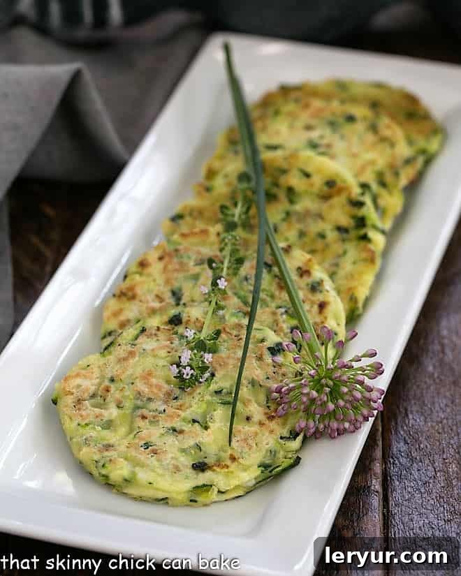 Crispy golden zucchini fritters displayed on an elegant white rectangle tray, ready to be served.