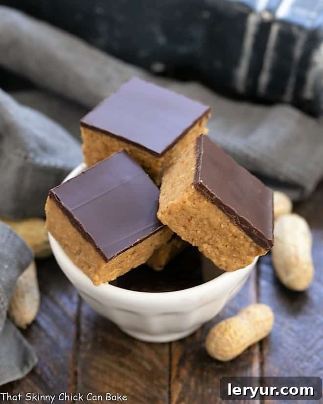 Better Than Reese's Peanut Butter Bars - Easy No-Bake Dessert for Chocolate & Peanut Butter Lovers Thick, decadent Better Than Reese's Peanut Butter Bars in a white bowl, showcasing layers of creamy peanut butter and rich chocolate.
