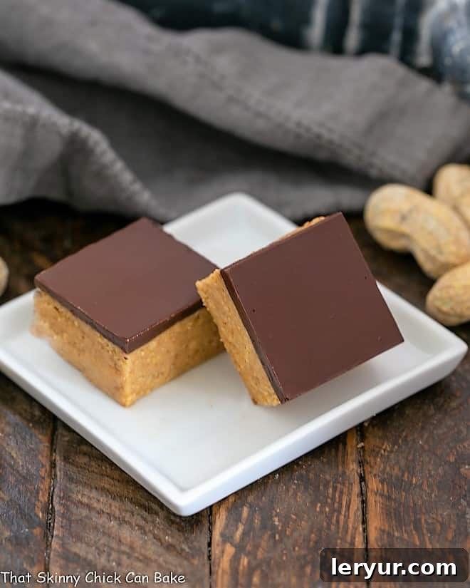 Perfectly Sliced No-Bake Chocolate Peanut Butter Bars Two neatly sliced Better Than Reese's Peanut Butter Bars on a small square white plate, showing the creamy peanut butter and smooth chocolate layers.