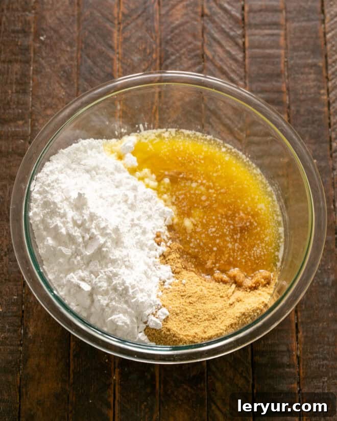 Forget Reeses: These Are The Best Peanut Butter Bars 4 Bowl containing powdered sugar, graham cracker crumbs, peanut butter, and melted butter, ready to be mixed.