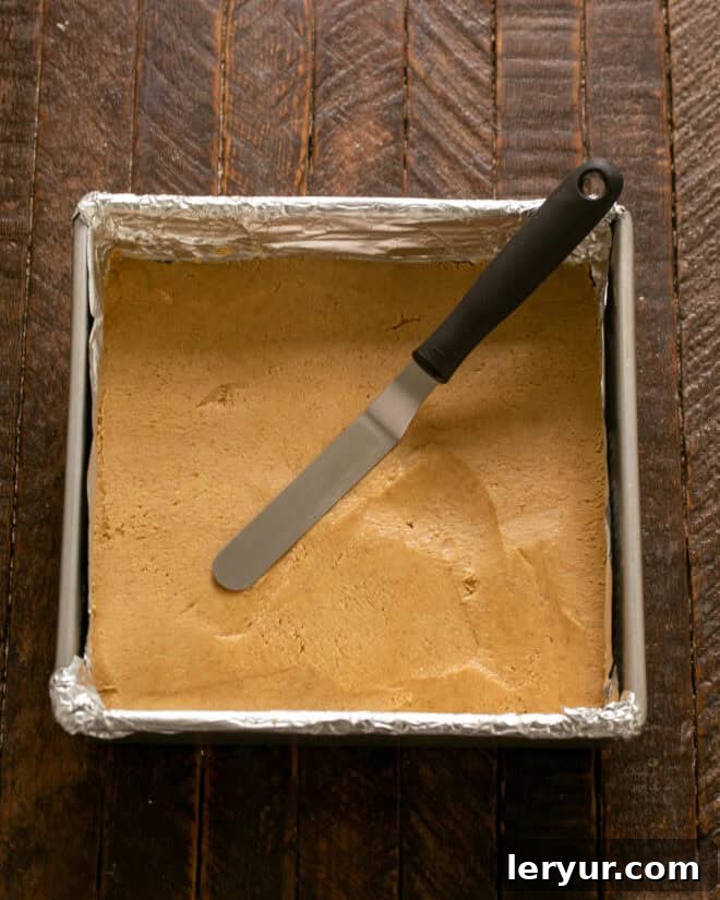 Forget Reeses: These Are The Best Peanut Butter Bars 6 Peanut butter mixture being firmly pressed into the bottom of the foil-lined baking pan.