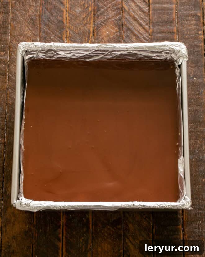 Forget Reeses: These Are The Best Peanut Butter Bars 8 Smooth, melted chocolate topping being spread evenly over the chilled peanut butter layer in the pan.