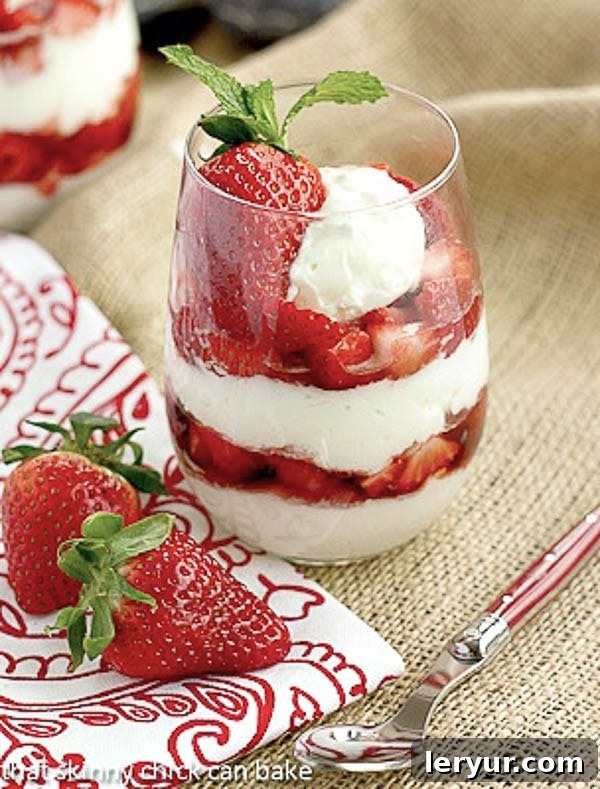 No-Bake Strawberry Cheesecake Parfaits - sweet luscious berries layered with dreamy cheesecake and topped with a dollop of cream for a beautiful, tasty treat! Strawberry Parfaits with a red handled spoon, red and white napkin and fresh strawberries, inviting and delicious.