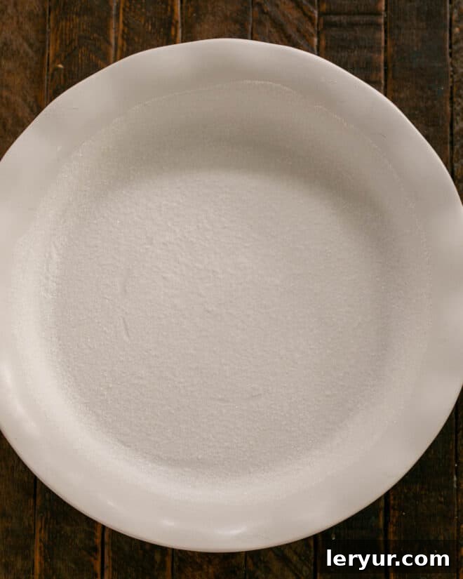 A ceramic baking dish generously buttered and coated with sugar, ready for the clafoutis batter.