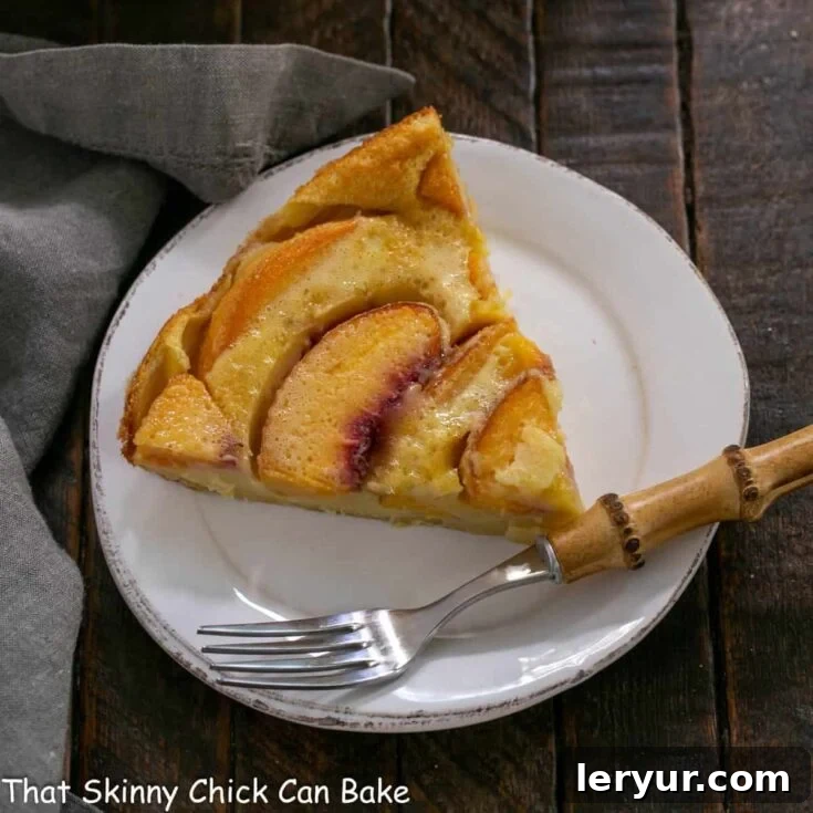 Overhead view of a slice of peach clafoutis, golden and inviting with a dusting of powdered sugar.