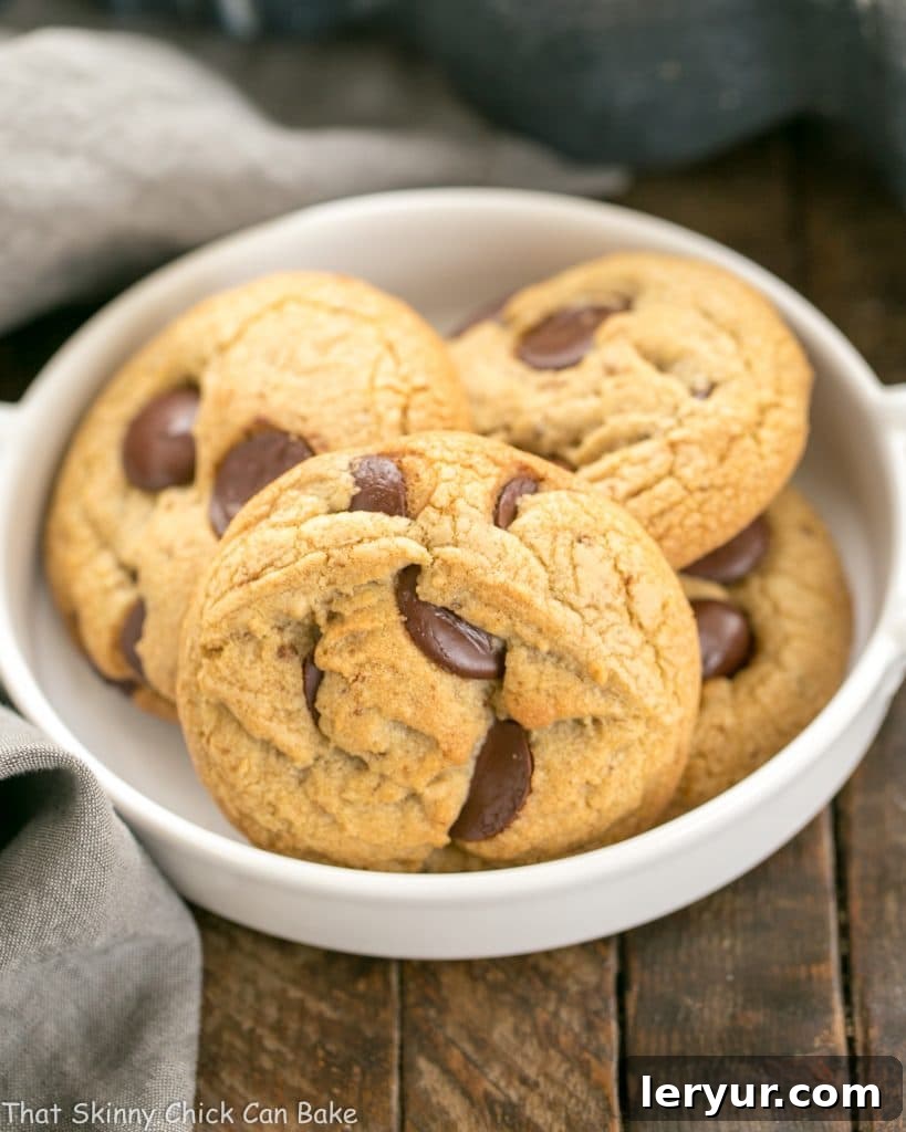 Divine Brown Butter Chocolate Chip Cookies 10 A close-up of several warm, freshly baked Brown Butter Chocolate Chip Cookies resting on a wire cooling rack, ready to be enjoyed with their rich, melted chocolate and golden-brown exterior.