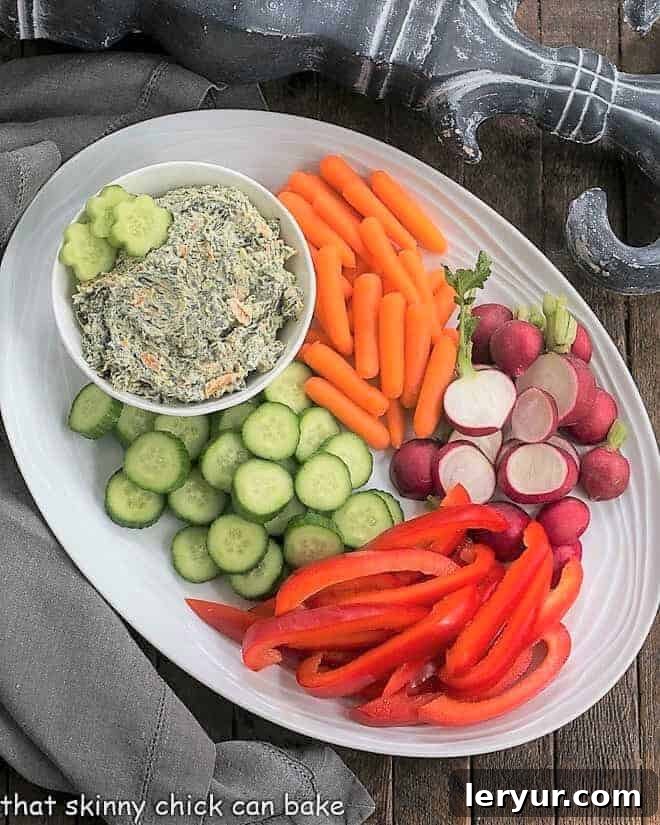 Creamy Sour Cream Spinach Dip - a delicious and easy-to-make homemade appetizer that's perfect for any party or family gathering, offering a burst of fresh flavor. A beautifully presented bowl of homemade Sour Cream Spinach Dip nestled on an oval white vegetable platter, surrounded by fresh, colorful crudités like carrots, celery, and bell peppers.