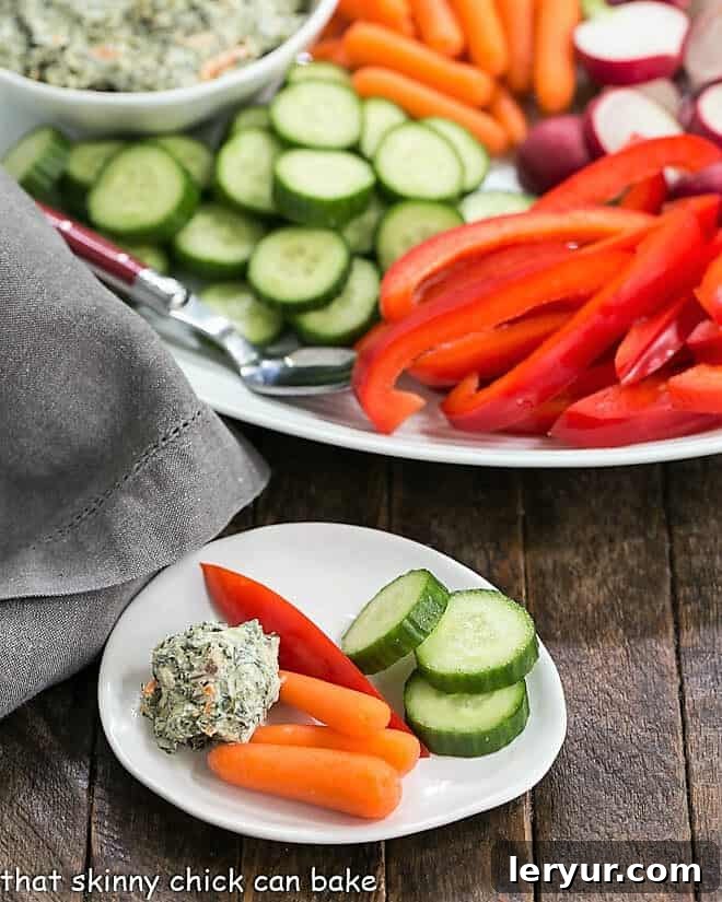 Elegant Sour Cream Spinach Dip - a versatile appetizer recipe that's ideal for entertaining guests or a delightful family treat, enhancing any crudité spread. A small appetizer dish features a dollop of creamy sour cream spinach dip, accompanied by fresh vegetable sticks like carrots and cucumbers, perfect for individual servings.