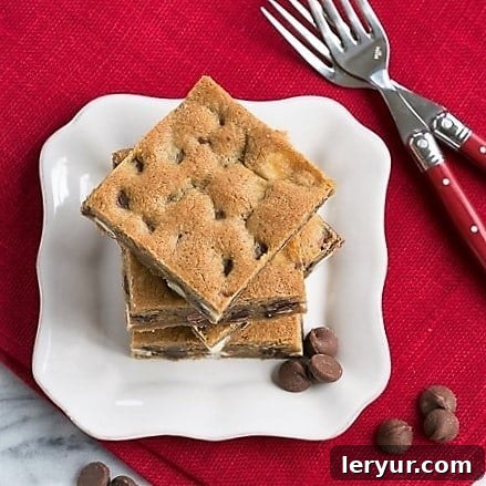 An inviting overhead shot of a generous stack of Homemade Chocolate Chip Bars, revealing a delightful array of three different kinds of chocolate chips embedded within each golden-brown square.