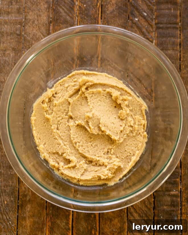 First step of baking: Creaming softened butter and both white and brown sugars together in a mixing bowl until light and fluffy.