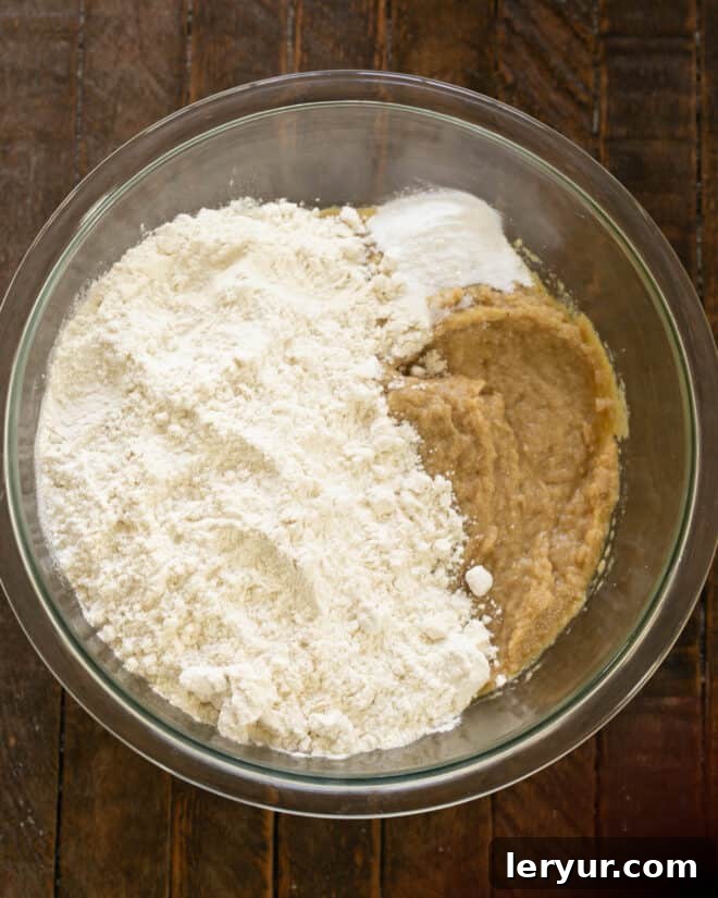 Incorporating dry ingredients like flour, baking soda, and salt into the wet mixture, ensuring a gradual and even blend.
