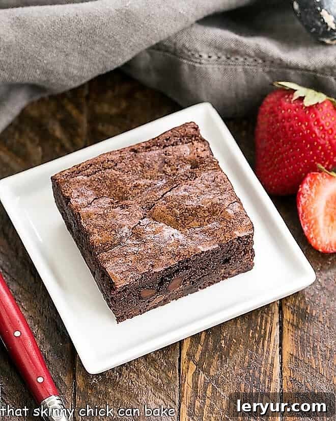 One fudgy sheet pan brownie on a square white plate, ready to be enjoyed.
