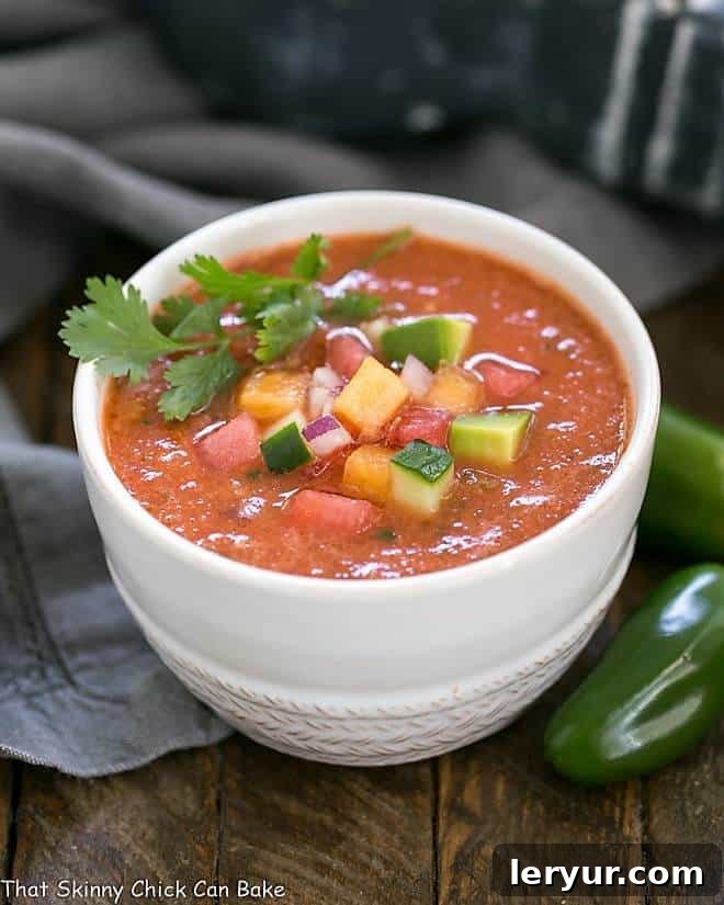 Wazpacho AKA watermelon gazpacho - A cold refreshing summer soup with tomatoes and watermelon! Wazpacho AKA watermelon gazpacho in a white ceramic bowl with jalapenos.