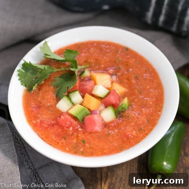 Wazpacho AKA watermelon gazpacho - A cold refreshing summer soup with tomatoes and watermelon! Wazpacho AKA watermelon gazpacho in a white bowl garnishes with avocado, melon and cucumber.