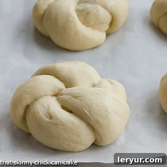 Yeast Roll Knots are super easy to make at home and so tender and delicious! Yeast Roll Knots neatly arranged on a baking sheet before going into the oven, showcasing their unique knotted shape.