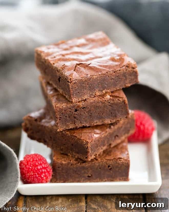 Best Fudgy Brownies - an extra step makes these dreamy and irresistible! Best Fudgy Brownies stacked on a white square plate.