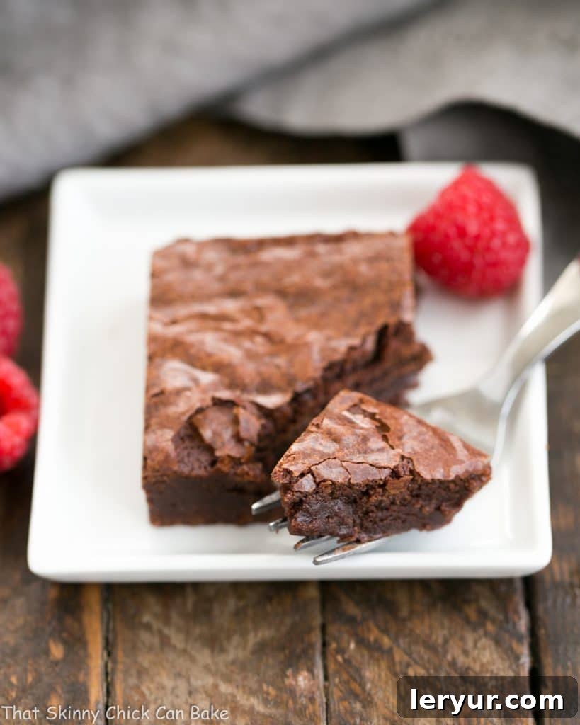 Best Fudgy Brownies - an extra step makes these dreamy and irresistible! Best Fudgy Brownies on a square plate with a fork removing a bite.