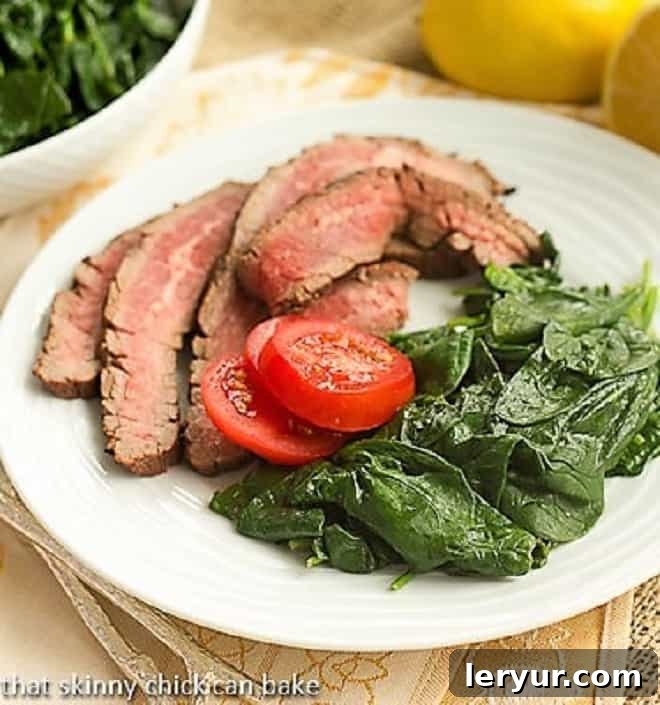 Shake up your side dishes with this super easy, tasty lemon steamed spinach recipe. This baby spinach recipe is a change of pace from your usual vegetables. Lemon Steamed Spinach on a white dinner plate garnished with fresh tomatoes