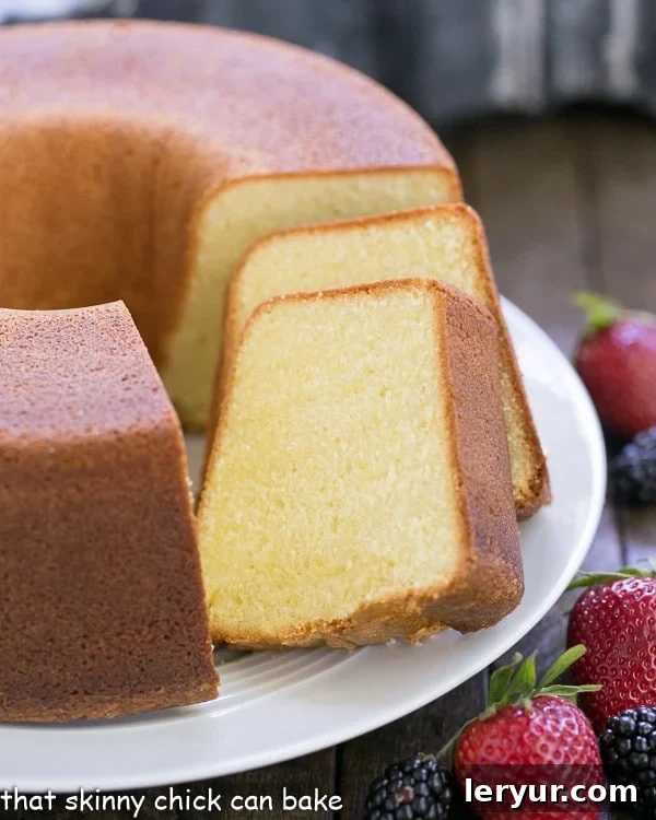 A stunning whole pound cake presented on a cake plate, with several perfectly cut slices ready to be enjoyed.
